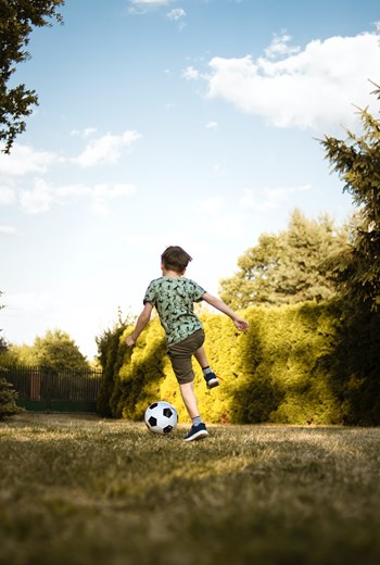 photo of boy practicing soccer alone