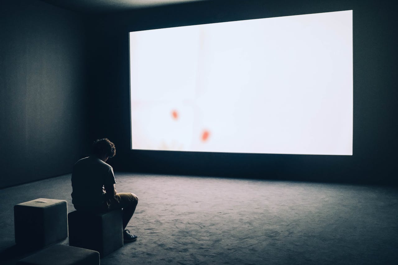 person sits in empty room with large screen